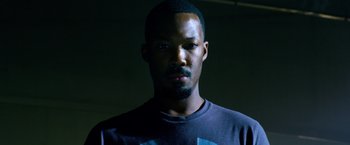 Movie still from “6 Underground” (2019), directed by Michael Bay – A man with a black t - shirt is in a dark room; Close Up shot, Low angle