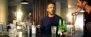 Movie still from “6 Underground” (2019), directed by Michael Bay – A man sitting at a table in front of a glass of water; Close Up shot, Over the shoulder angle