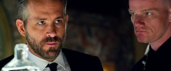 Movie still from “6 Underground” (2019), directed by Michael Bay – A person wearing a suit and tie; Close Up shot, Over the shoulder angle