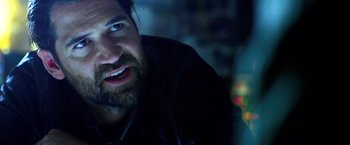 Movie still from “6 Underground” (2019), directed by Michael Bay – A man with a goatee is smiling for the camera; Close Up shot, Over the shoulder angle