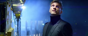 Movie still from “6 Underground” (2019), directed by Michael Bay – A man in a black suit looking up at the sky; Close Up shot, Low angle