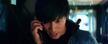 Movie still from “6 Underground” (2019), directed by Michael Bay – A young man talking on a cell phone while wearing a black jacket; Close Up shot, Low angle