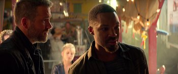 Movie still from “6 Underground” (2019), directed by Michael Bay – A person in a room with other people; Close Up shot, Over the shoulder angle