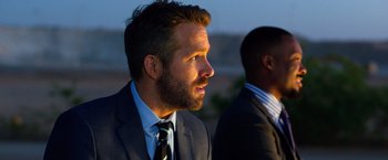 Movie still from “6 Underground” (2019), directed by Michael Bay – A man in a suit and tie looking to his left; Close Up shot, Over the shoulder angle