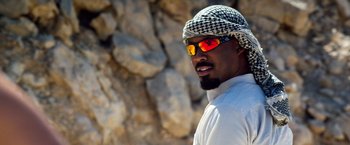 Movie still from “6 Underground” (2019), directed by Michael Bay – A man with a beard wearing sunglasses and a head scarf; Close Up shot, Low angle