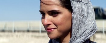 Movie still from “6 Underground” (2019), directed by Michael Bay – A woman's face with a scarf around her head; Close Up shot, Over the shoulder angle