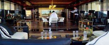 Movie still from “6 Underground” (2019), directed by Michael Bay – A person sitting at a table in a restaurant; Extreme Wide shot, Over the shoulder angle