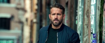 Movie still from “6 Underground” (2019), directed by Michael Bay – A person wearing a jacket; Close Up shot, Over the shoulder angle