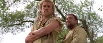 Movie still from “A Knight's Tale” (2001), directed by Brian Helgeland – Two men standing next to each other near a tree; Medium shot, Low angle