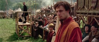 Movie still from “A Knight's Tale” (2001), directed by Brian Helgeland – A crowd of people gathered around a man in medieval garb; Medium shot, Low angle