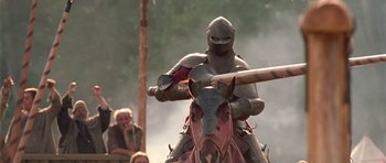 Movie still from “A Knight's Tale” (2001), directed by Brian Helgeland – A man riding on the back of a brown horse; Medium shot, Low angle