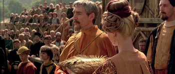 Movie still from “A Knight's Tale” (2001), directed by Brian Helgeland – A man and a woman are standing in front of a crowd; Medium shot, Over the shoulder angle