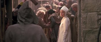 Movie still from “A Knight's Tale” (2001), directed by Brian Helgeland – A woman wearing a white coat and a white hood; Medium shot, Over the shoulder angle
