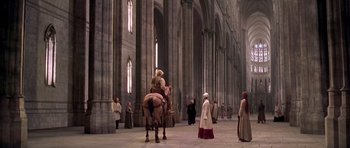 Movie still from “A Knight's Tale” (2001), directed by Brian Helgeland – A man riding a horse inside of a building; Extreme Wide shot, High angle