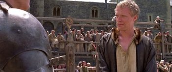Movie still from “A Knight's Tale” (2001), directed by Brian Helgeland – A man standing in front of a group of people; Medium shot, Over the shoulder angle