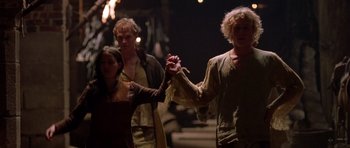 Movie still from “A Knight's Tale” (2001), directed by Brian Helgeland – A man and a woman holding hands while another man looks on; Medium shot, Low angle