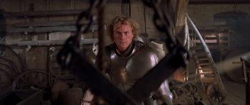 Movie still from “A Knight's Tale” (2001), directed by Brian Helgeland – A man wearing a suit of armor and holding a sword; Medium shot, High angle