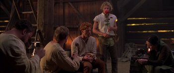 Movie still from “A Knight's Tale” (2001), directed by Brian Helgeland – A group of men sitting on the ground in a room; Medium shot, Over the shoulder angle