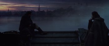 Movie still from “A Knight's Tale” (2001), directed by Brian Helgeland – A person sitting on a bench near a body of water at night; Wide shot, Low angle