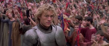Movie still from “A Knight's Tale” (2001), directed by Brian Helgeland – A man wearing a suit of armor standing in front of a crowd; Medium shot, High angle
