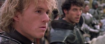 Movie still from “A Knight's Tale” (2001), directed by Brian Helgeland – A man's face with a man in the background looking to his left; Close Up shot, Over the shoulder angle