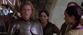 Movie still from “A Knight's Tale” (2001), directed by Brian Helgeland – A man and a woman standing next to each other in front of a stone wall; Close Up shot, Over the shoulder angle