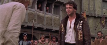 Movie still from “A Knight's Tale” (2001), directed by Brian Helgeland – A group of people standing in front of a building; Medium shot, Over the shoulder angle