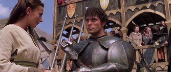 Movie still from “A Knight's Tale” (2001), directed by Brian Helgeland – A man wearing a suit of armor standing in front of a crowd; Medium shot, Low angle