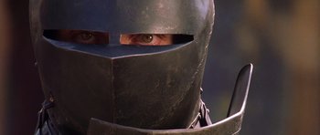 Movie still from “A Knight's Tale” (2001), directed by Brian Helgeland – A person wearing a metal helmet and looking at the camera; Close Up shot, Low angle