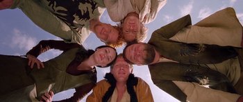 Movie still from “A Knight's Tale” (2001), directed by Brian Helgeland – A group of people standing in a circle with their heads together; Medium shot, Overhead angle