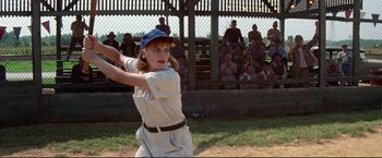 Movie still from “A League of Their Own” (1992), directed by Penny Marshall – A young girl swinging a baseball bat at a game; Medium shot, Low angle