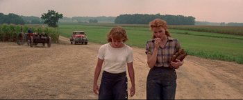 Movie still from “A League of Their Own” (1992), directed by Penny Marshall – Two women walking on a dirt road near a field; Medium shot, Over the shoulder angle