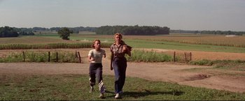 Movie still from “A League of Their Own” (1992), directed by Penny Marshall – Two women are running in a field together; Wide shot, Over the shoulder angle