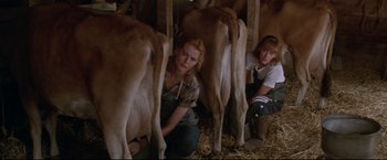Movie still from “A League of Their Own” (1992), directed by Penny Marshall – Two women milking a cow in a barn; Medium shot, High angle