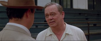 Movie still from “A League of Their Own” (1992), directed by Penny Marshall – An older man wearing a white shirt talking to a man in a brown hat; Close Up shot, Over the shoulder angle