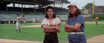 Movie still from “A League of Their Own” (1992), directed by Penny Marshall – A woman in a baseball uniform standing next to another woman in a baseball uniform; Medium shot, Low angle