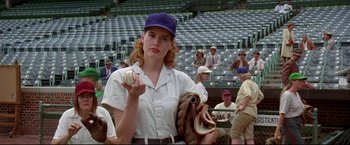 Movie still from “A League of Their Own” (1992), directed by Penny Marshall – A woman in a baseball uniform holding a ball and a mitt; Medium shot, Low angle