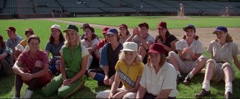 Movie still from “A League of Their Own” (1992), directed by Penny Marshall – A group of people sitting on the grass at a baseball field; Wide shot, High angle