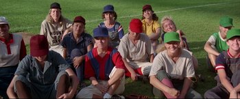 Movie still from “A League of Their Own” (1992), directed by Penny Marshall – A group of people sitting on the grass wearing baseball uniforms; Wide shot, High angle