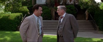 Movie still from “A League of Their Own” (1992), directed by Penny Marshall – Two men in suits talking to each other outside; Medium shot, Over the shoulder angle