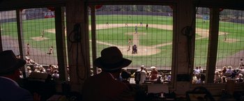 Movie still from “A League of Their Own” (1992), directed by Penny Marshall – A man wearing a brown hat watching a baseball game; Extreme Wide shot, High angle