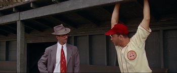 Movie still from “A League of Their Own” (1992), directed by Penny Marshall – Two men in suits and hats are standing in front of one another; Medium shot, Low angle