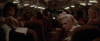 Movie still from “A League of Their Own” (1992), directed by Penny Marshall – A woman sitting on a train looking at the camera; Close Up shot, Over the shoulder angle
