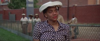 Movie still from “A League of Their Own” (1992), directed by Penny Marshall – An older woman wearing a white hat and a polka dot shirt; Close Up shot, Over the shoulder angle