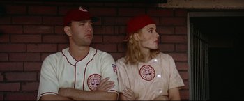 Movie still from “A League of Their Own” (1992), directed by Penny Marshall – A man and a woman sitting next to each other in baseball uniforms; Medium shot, Low angle