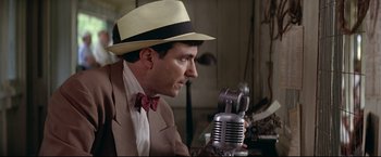 Movie still from “A League of Their Own” (1992), directed by Penny Marshall – A man wearing a hat looking at a microphone; Close Up shot, Low angle