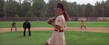 Movie still from “A League of Their Own” (1992), directed by Penny Marshall – A woman in a baseball uniform holding a catchers mitt on a baseball field; Medium shot, Over the shoulder angle