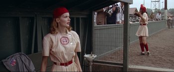 Movie still from “A League of Their Own” (1992), directed by Penny Marshall – A woman in a baseball uniform standing in front of a fence; Medium shot, Low angle
