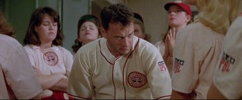 Movie still from “A League of Their Own” (1992), directed by Penny Marshall – A man in a baseball uniform sitting in front of a group of people; Medium shot, Low angle