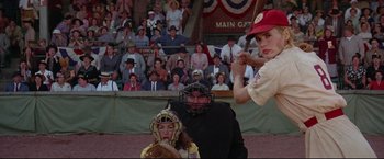 Movie still from “A League of Their Own” (1992), directed by Penny Marshall – A baseball player holding a bat next to a catcher and umpire; Medium shot, Over the shoulder angle